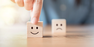 two wooden cubes with a happy and sad face drawn on