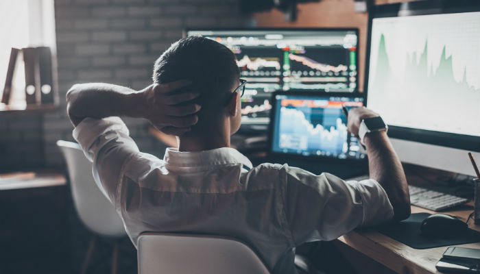 man looking at stock markets on computer screens
