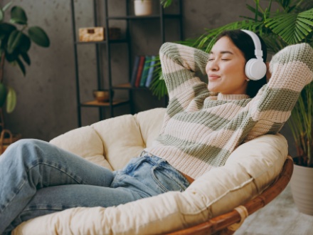 young woman in armchair listening on headphone