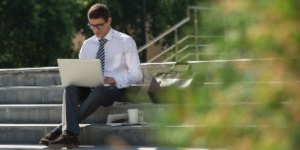 man in suit outside on laptop