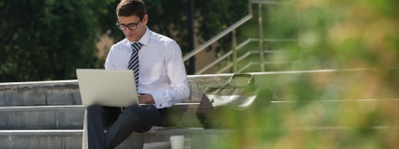man in suit outside on laptop
