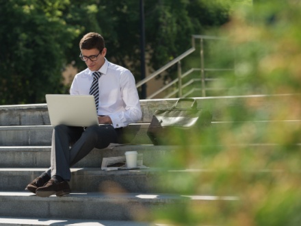 man in suit outside on laptop
