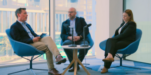 Three people sit around a table recording a vodcast
