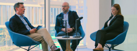 Three people sit around a table recording a vodcast