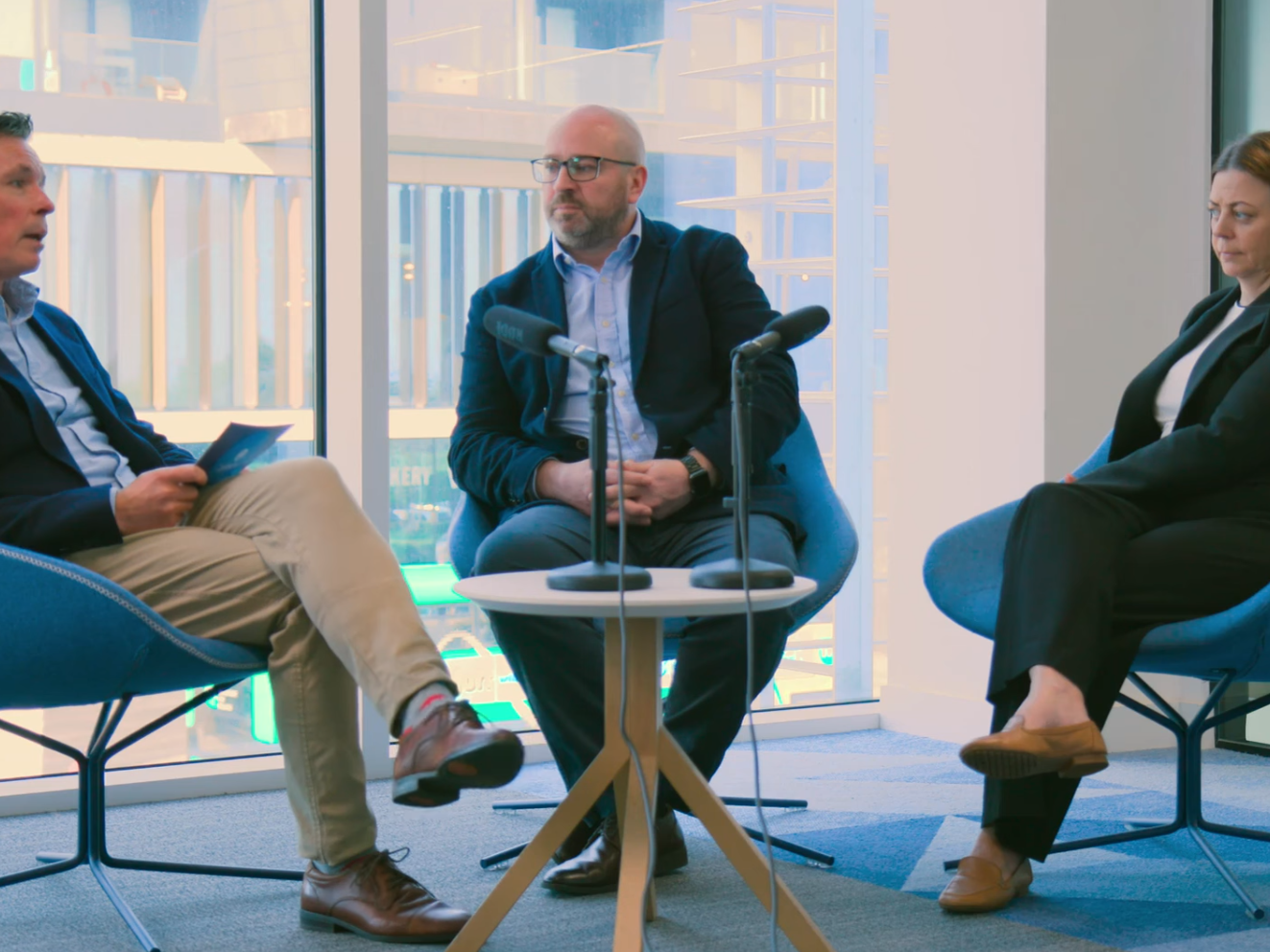 Three people sit around a table recording a vodcast