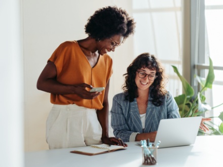 two woman in office looking at laptop