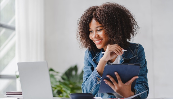 African woman at desk looking at laptop