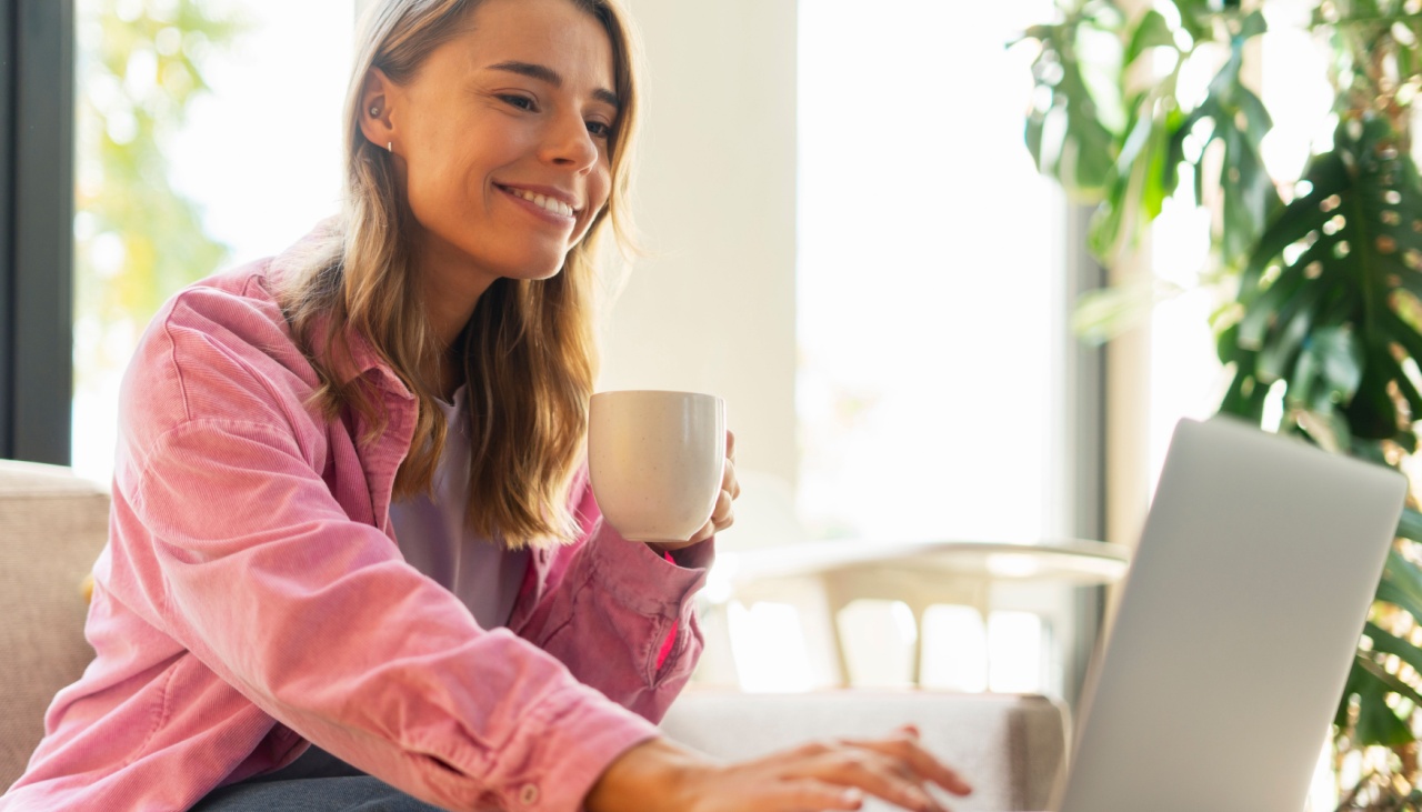 smiling woman having coffee at her laptop