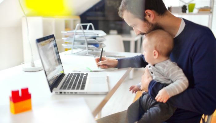 father at home office working with child on his lap