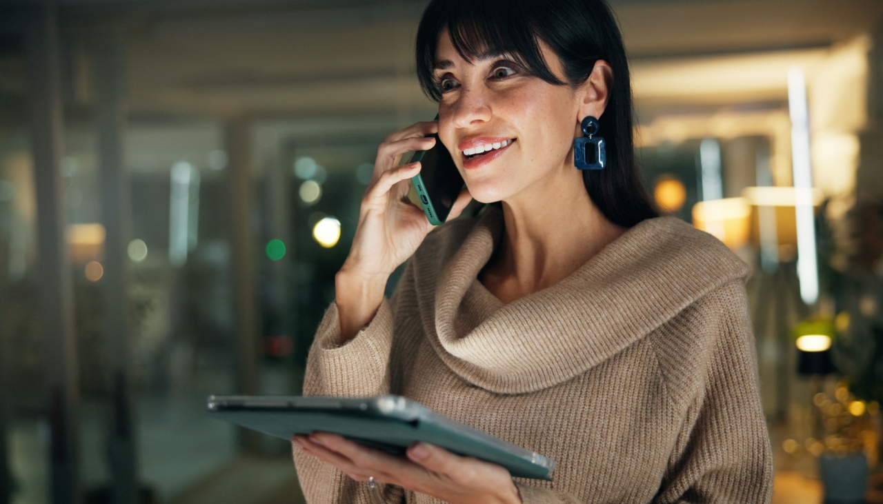 smiling woman on phone with tablet in her hand