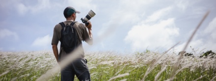 Cameraman standing holding camera in the middle of a meadow