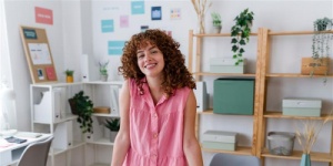 Woman smiling in pink top at home office desk
