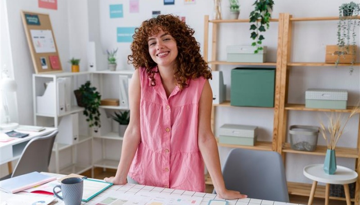 Woman smiling in pink top at home office desk