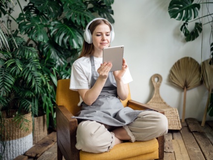 woman at listening to a podcast with plants in the background
