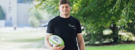 Rugby player Jack O’Donoghue holding a rugby ball with Tackle your feelings written on it