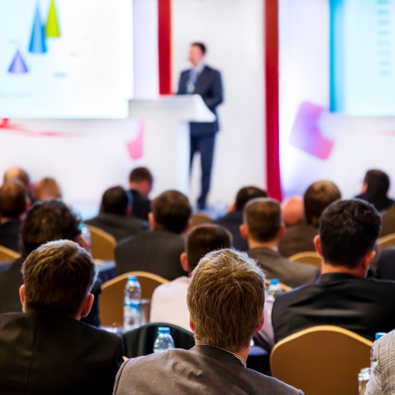 Business event photo of speaker at podium with seated audience