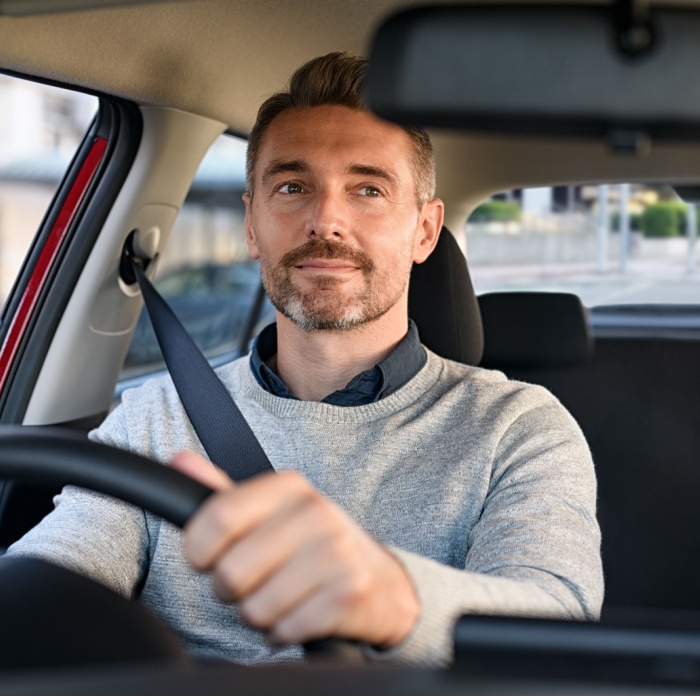 Man sitting in car checking his rear view mirror