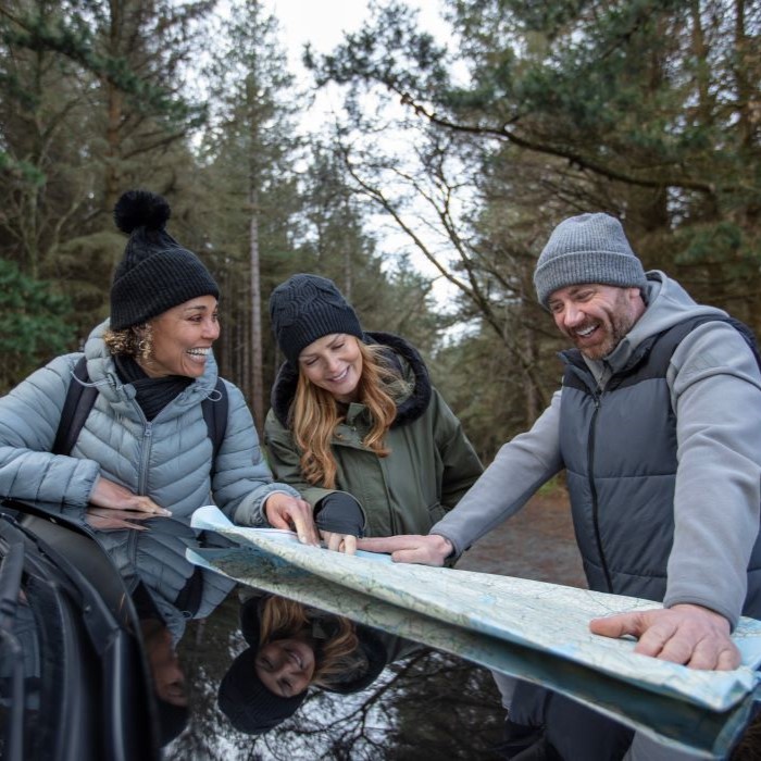 3 people looking at a map outside a car