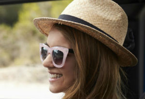 A woman wearing sunglasses and a sun hat driving a car