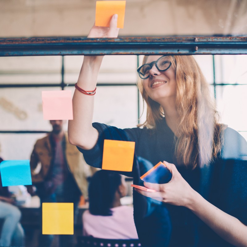 office worker putting post it notes on window