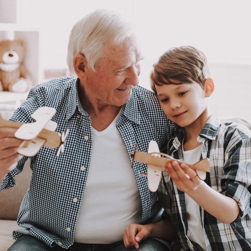 grandfather and grandson playing with paper planes