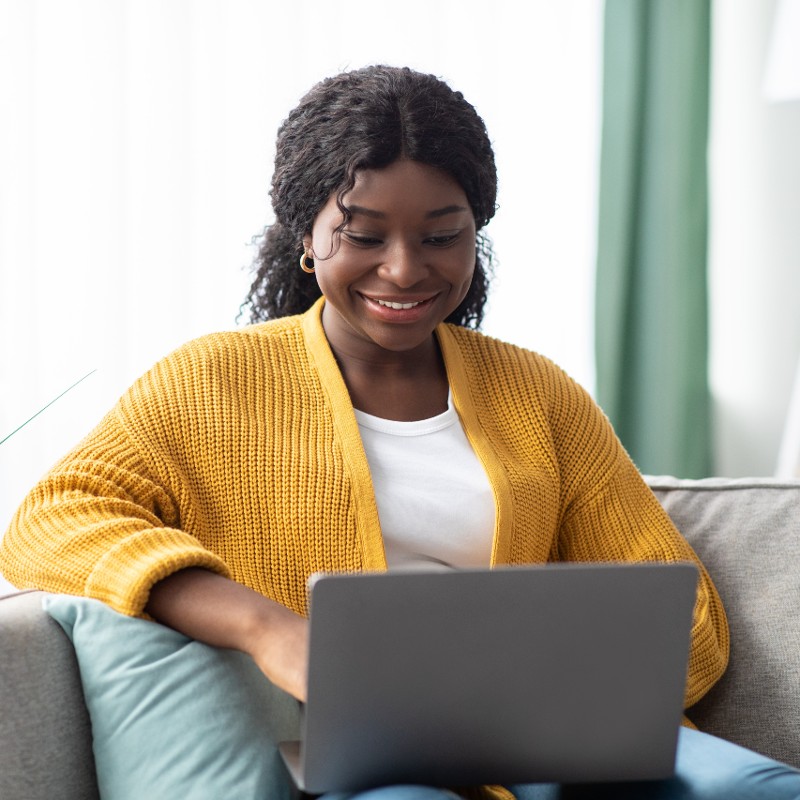 woman on laptop in mustard jumper