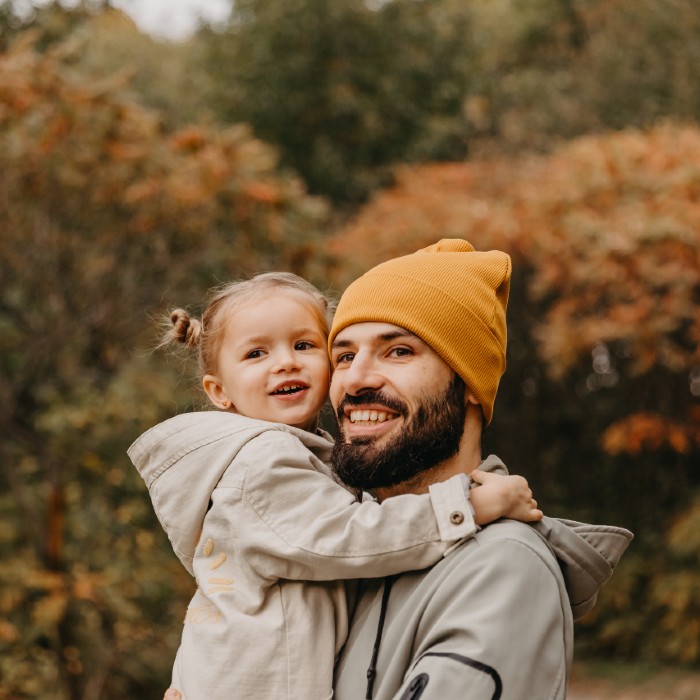 Young father wearing yellow hat, carrying his daughter