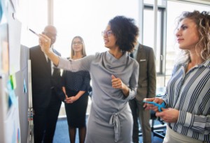 two woman at white board in office