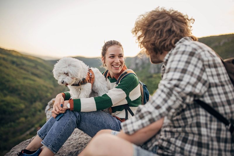 couple with dog resting on mountain